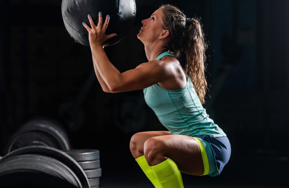 woman-athlete-exercising-with-medicine-ball-PYB74ZY
